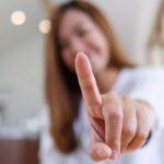 A young Asian woman holding up her index finger