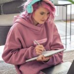 Young Caucasian woman with pink her studying from her laptop screen