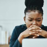 Young Black woman looking concerned while in front of her laptop