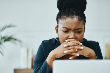 Young Black woman looking concerned while in front of her laptop