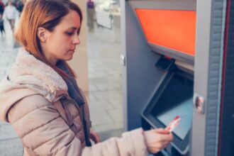 Young Caucasian woman at the street withdrawing money at the ATM