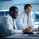 Engineer Project Manager Talks With Scientist working on Computer