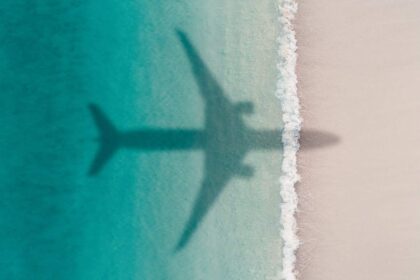 Aerial shot showing an aircraft shadow flying over an idyllic beach