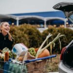 Young happy white woman loading groceries into the back of her car