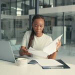 Shot of a young Black woman doing some paperwork in a modern office